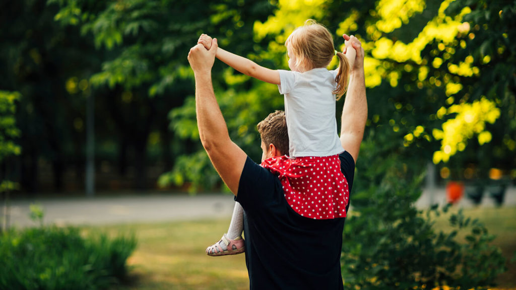 Homem curado da capsulite adesiva carregando a filha acima do ombro