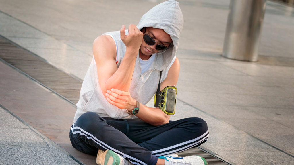 Jovem praticante de parkour com dor no cotovelo por causa da epicondilite