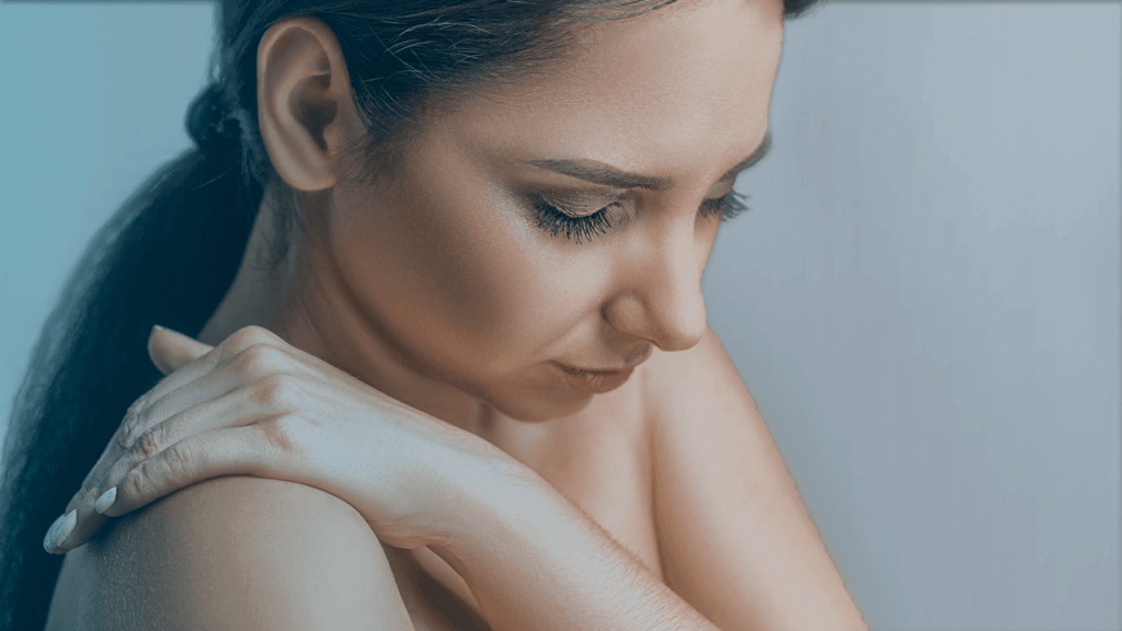 Mulher jovem com dor no ombro por conta da capsulite adesiva